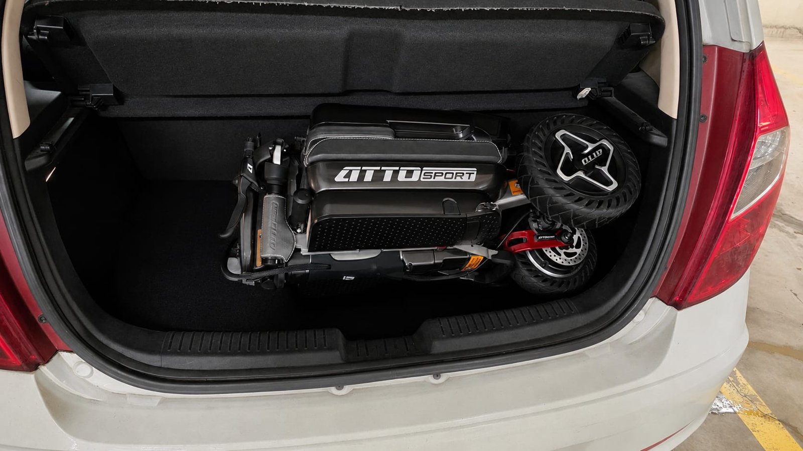 Hyundai i10 (2019-2024) boot with a folded ATTO mobility scooter ATTO Sport folding mobility scooter folded in the boot of a Hyundai i10 city car — fits with the parcel shelf in place